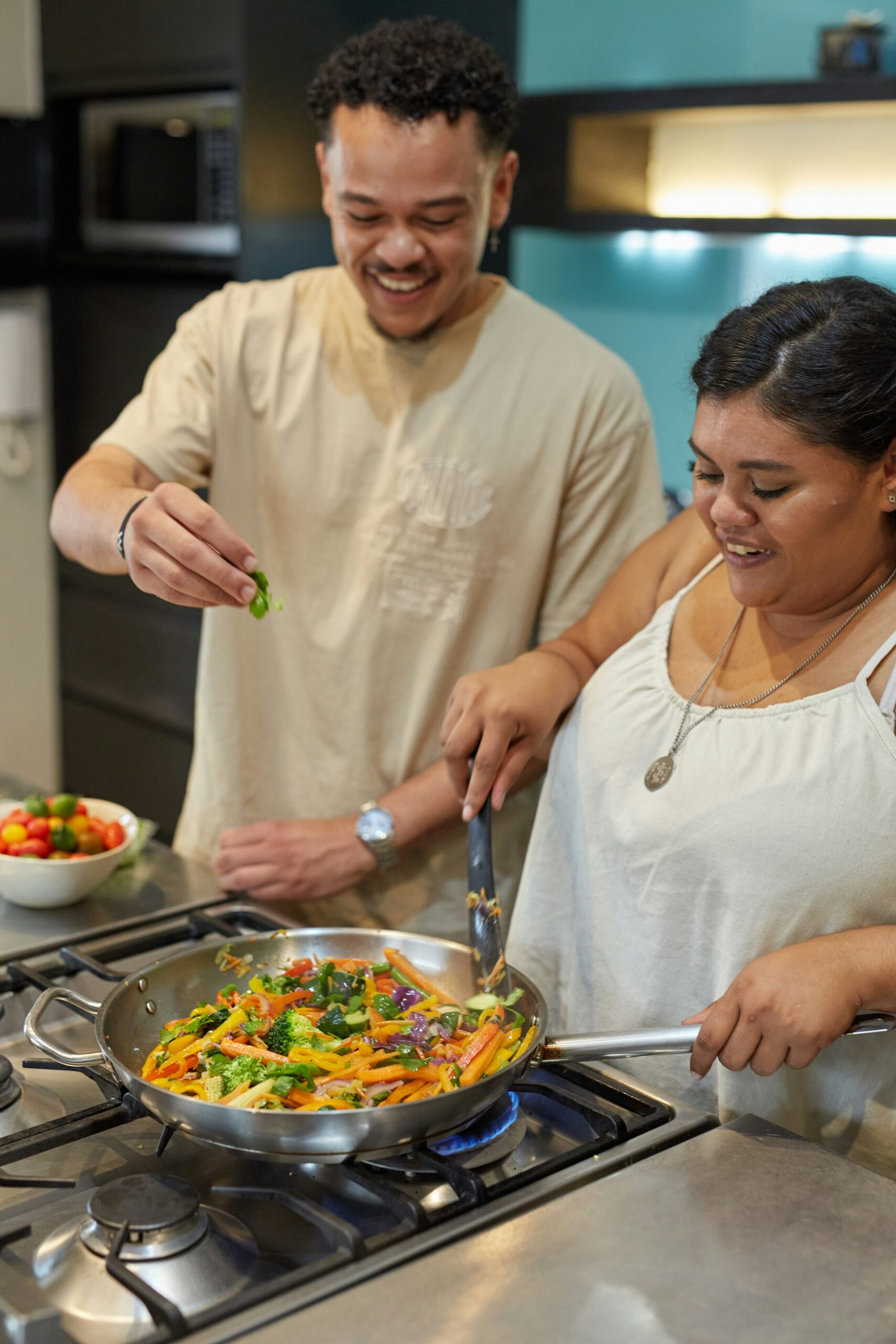 A man and woman cooking in a kitchen while smiling.